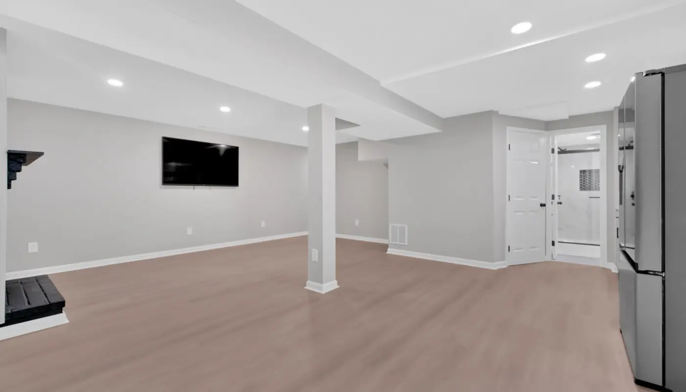 Finished basement with new flooring, recessed lighting and a wet bar beyond