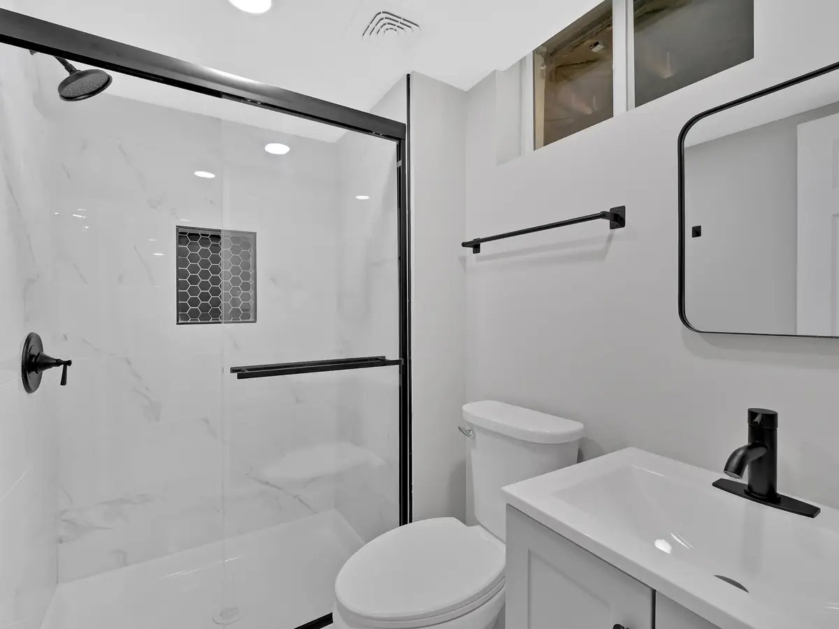 Remodeled bathroom with a tiled walk-in shower, black fixtures and a floating vanity