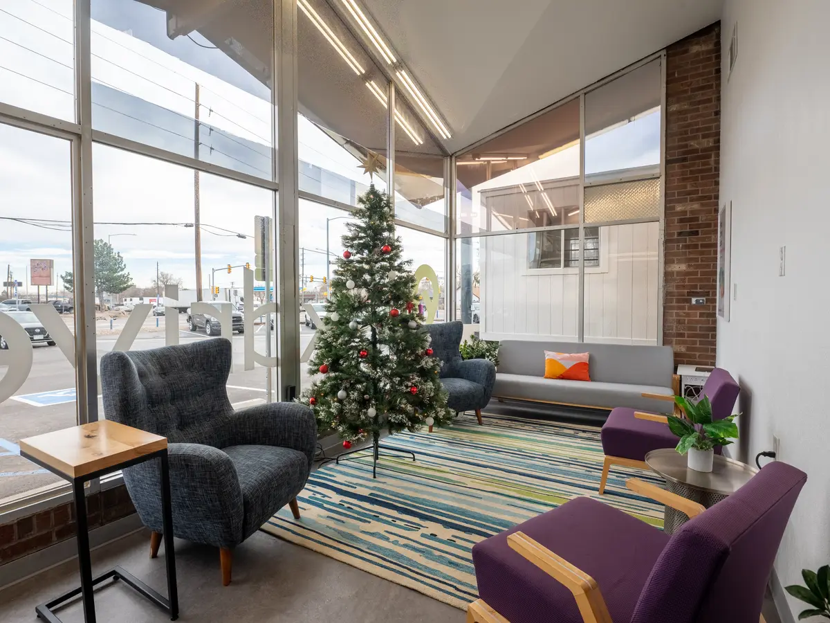 Front lounge with full height windows, lounge chairs and exposed brick